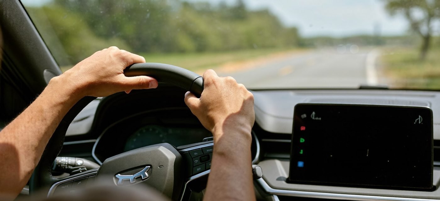 Manos al volante de un carro en la carretera